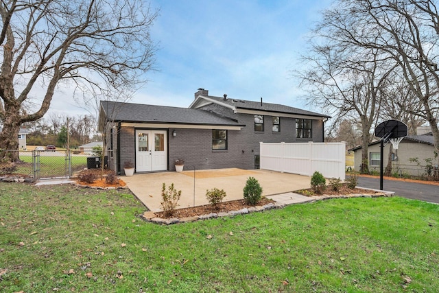 back of house featuring a gate, fence, a lawn, a patio area, and brick siding