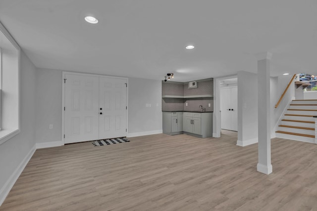 interior space featuring baseboards, light wood finished floors, recessed lighting, a sink, and stairs