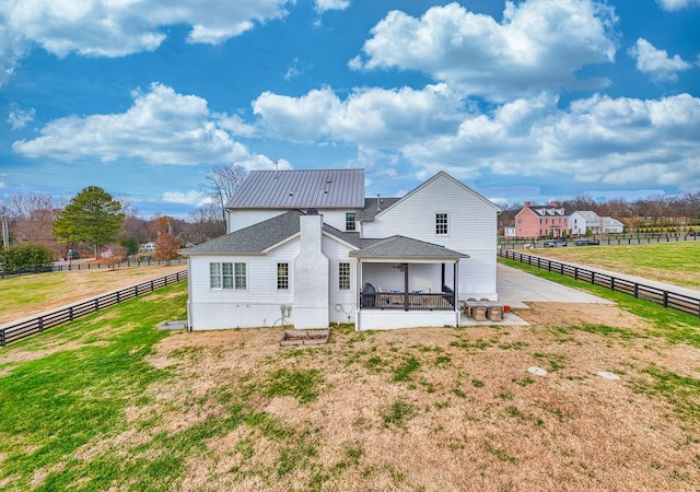 back of house featuring a yard, a rural view, and a patio