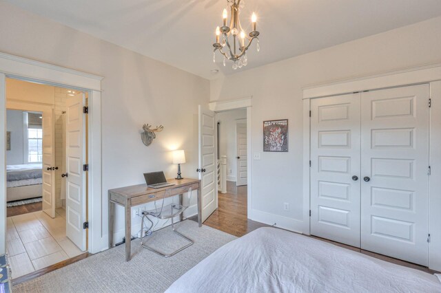 bedroom with a closet, an inviting chandelier, and light wood-type flooring