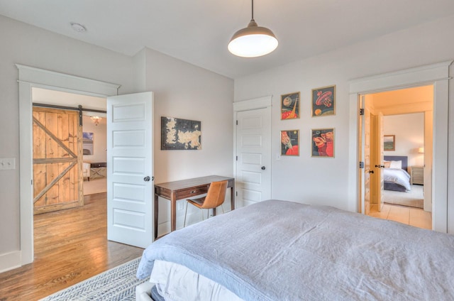 bedroom with hardwood / wood-style flooring and a barn door