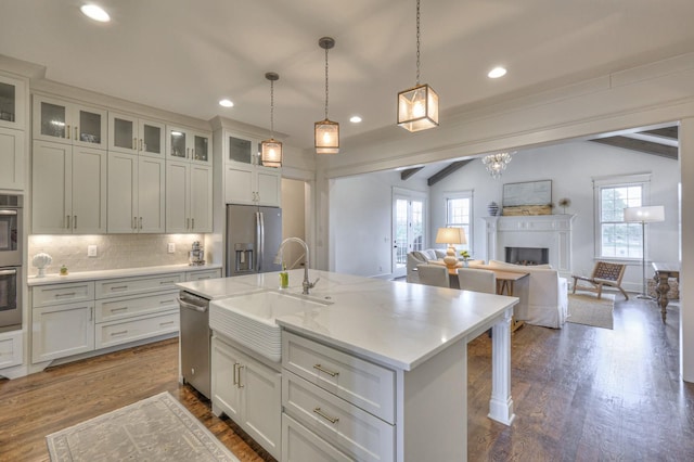 kitchen featuring appliances with stainless steel finishes, pendant lighting, a center island with sink, and a healthy amount of sunlight