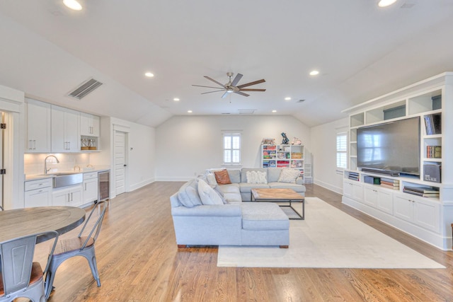 living room featuring ceiling fan, sink, beverage cooler, light hardwood / wood-style flooring, and lofted ceiling