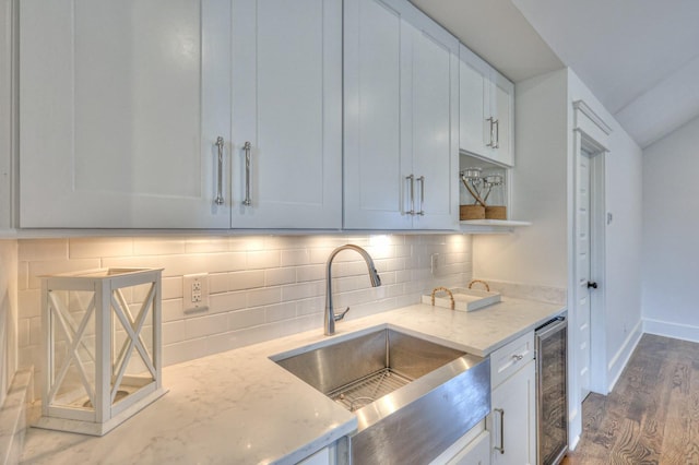 kitchen with hardwood / wood-style floors, sink, decorative backsplash, light stone countertops, and white cabinetry