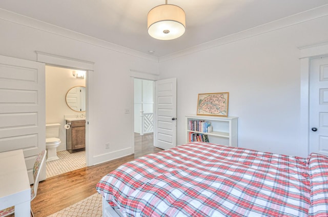 bedroom featuring ensuite bathroom, light hardwood / wood-style flooring, and ornamental molding