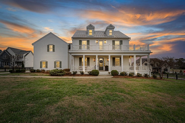 view of front facade featuring a porch, a balcony, and a lawn