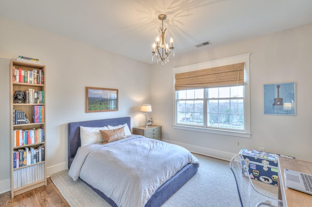 bedroom with wood-type flooring and an inviting chandelier