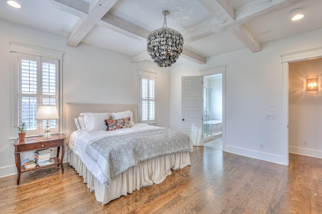 bedroom with multiple windows, hardwood / wood-style floors, ensuite bath, and beamed ceiling