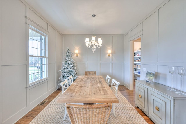 dining area with hardwood / wood-style floors, plenty of natural light, and a notable chandelier