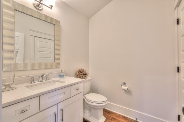 bathroom with hardwood / wood-style floors, vanity, toilet, and vaulted ceiling