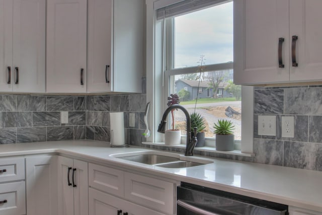 kitchen with decorative backsplash, dishwashing machine, sink, and white cabinets