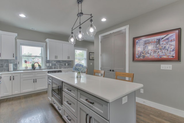 kitchen featuring dark hardwood / wood-style flooring, a center island, white cabinetry, and sink