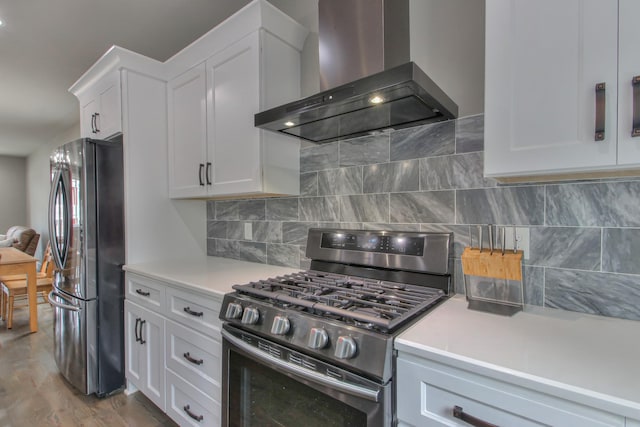 kitchen with stainless steel appliances, wall chimney range hood, backsplash, hardwood / wood-style floors, and white cabinets