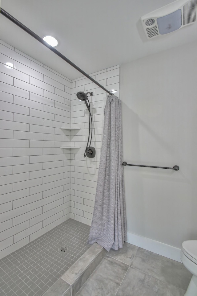 bathroom with a shower with shower curtain, tile patterned floors, and toilet