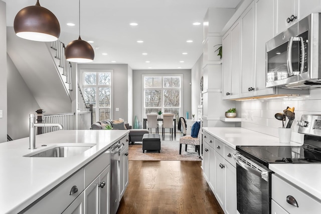 kitchen with sink, white cabinets, decorative light fixtures, dark hardwood / wood-style flooring, and stainless steel appliances