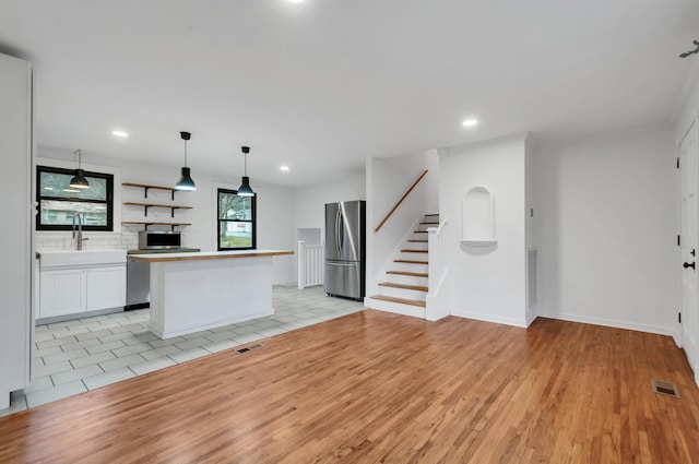 kitchen with a center island, sink, light hardwood / wood-style flooring, white cabinetry, and stainless steel appliances