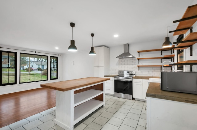 kitchen with light wood-type flooring, wall chimney range hood, white cabinetry, butcher block countertops, and stainless steel electric range oven