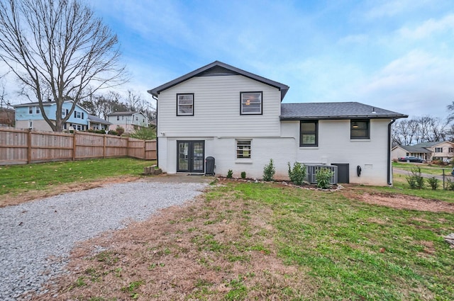 rear view of house with a lawn, central AC, and french doors