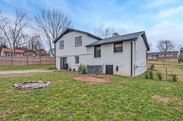 rear view of house featuring a lawn, cooling unit, and a fire pit