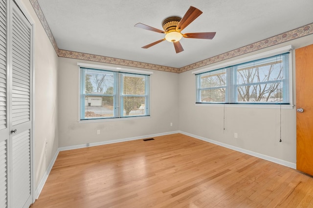 unfurnished bedroom with a closet, a textured ceiling, light hardwood / wood-style floors, and ceiling fan