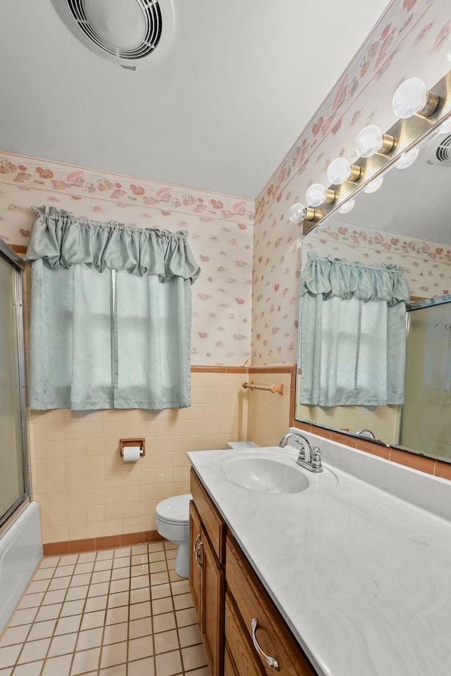 full bathroom featuring vanity, tile patterned floors, combined bath / shower with glass door, toilet, and tile walls