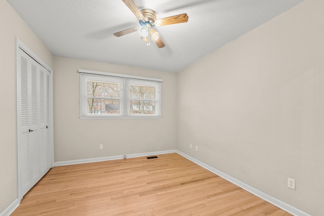 unfurnished bedroom with ceiling fan, light hardwood / wood-style floors, a textured ceiling, and a closet