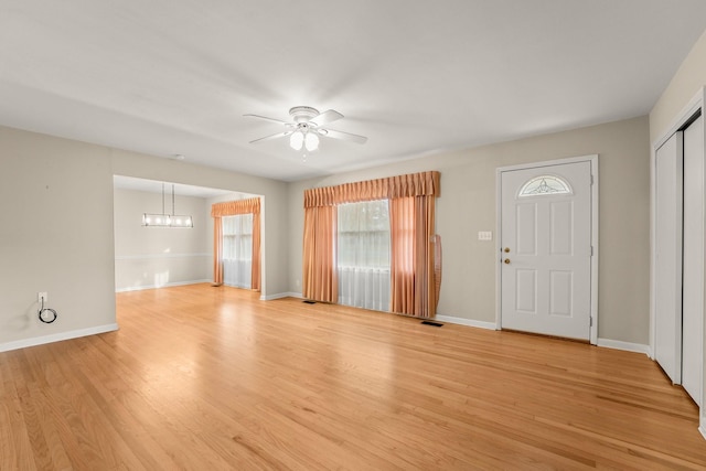 entryway with ceiling fan with notable chandelier and light hardwood / wood-style flooring