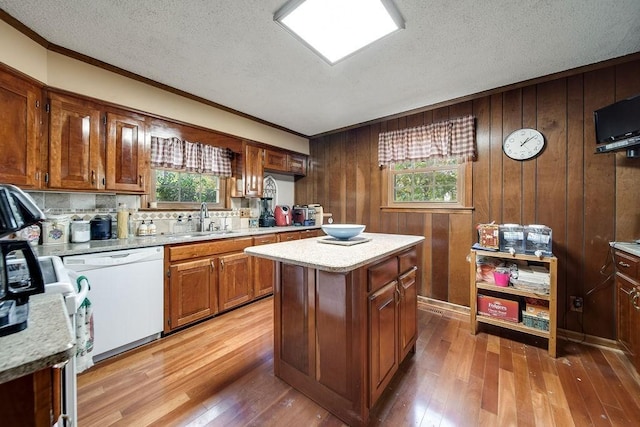 kitchen featuring white dishwasher, a kitchen island, plenty of natural light, and wood walls