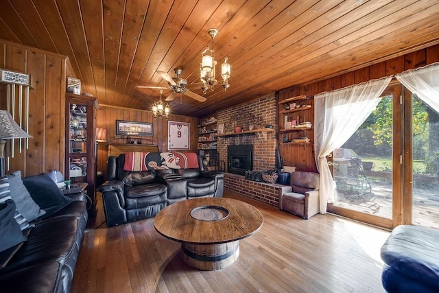 living room with a wood stove, wooden walls, ceiling fan, built in features, and light wood-type flooring