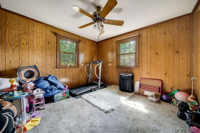 workout room with carpet flooring, wood walls, and a textured ceiling