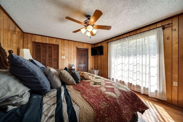 bedroom featuring ceiling fan, wood walls, and a textured ceiling