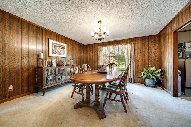 carpeted dining area with a chandelier, ornamental molding, a textured ceiling, and wooden walls