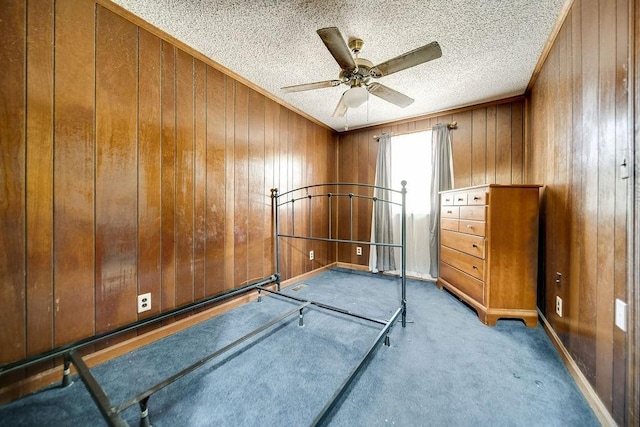 bedroom featuring carpet flooring, ceiling fan, wood walls, and a textured ceiling