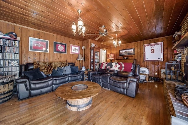 living room with wood-type flooring, ceiling fan with notable chandelier, wooden ceiling, and wood walls