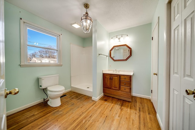 bathroom with an inviting chandelier, hardwood / wood-style flooring, toilet, a textured ceiling, and walk in shower