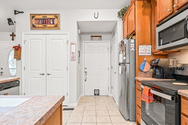 kitchen with appliances with stainless steel finishes, backsplash, and light tile patterned flooring