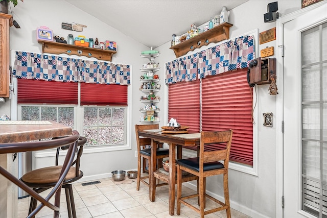 tiled dining room featuring vaulted ceiling