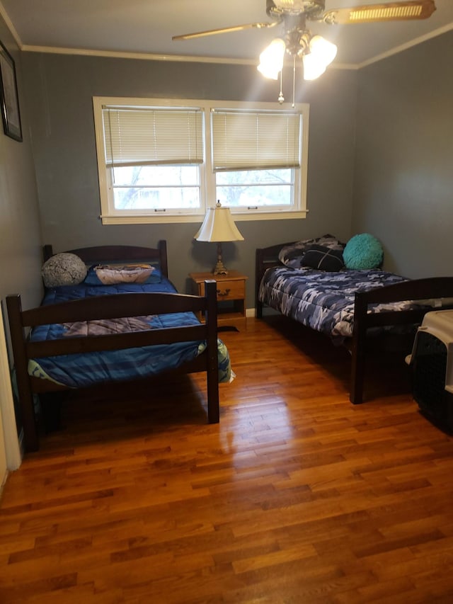 bedroom with hardwood / wood-style floors, ceiling fan, and crown molding