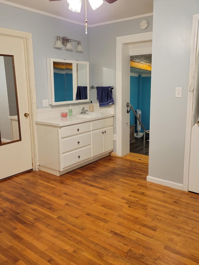 bathroom featuring hardwood / wood-style flooring, ceiling fan, crown molding, and vanity