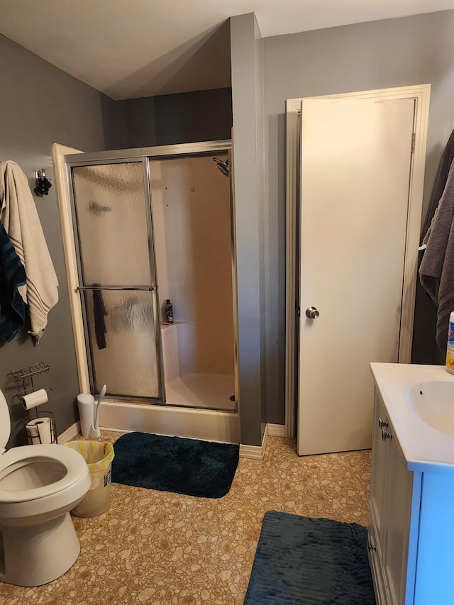 bathroom with vanity, toilet, and a shower with door