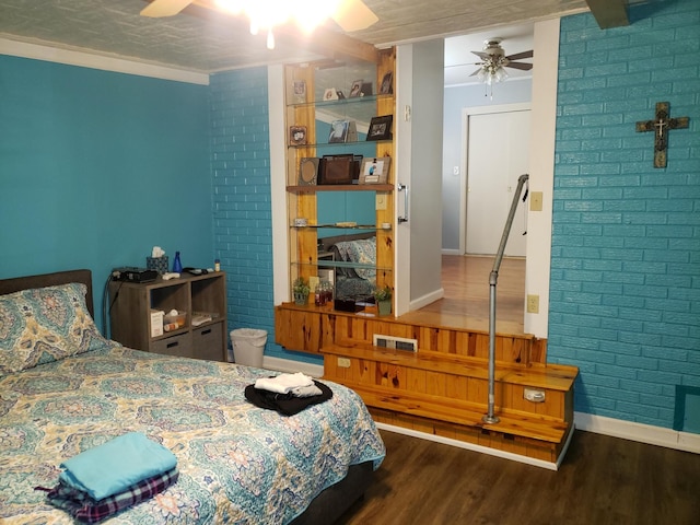 bedroom with ceiling fan, crown molding, brick wall, and dark hardwood / wood-style floors