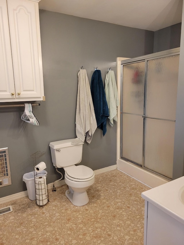 bathroom featuring vanity, toilet, an enclosed shower, and heating unit