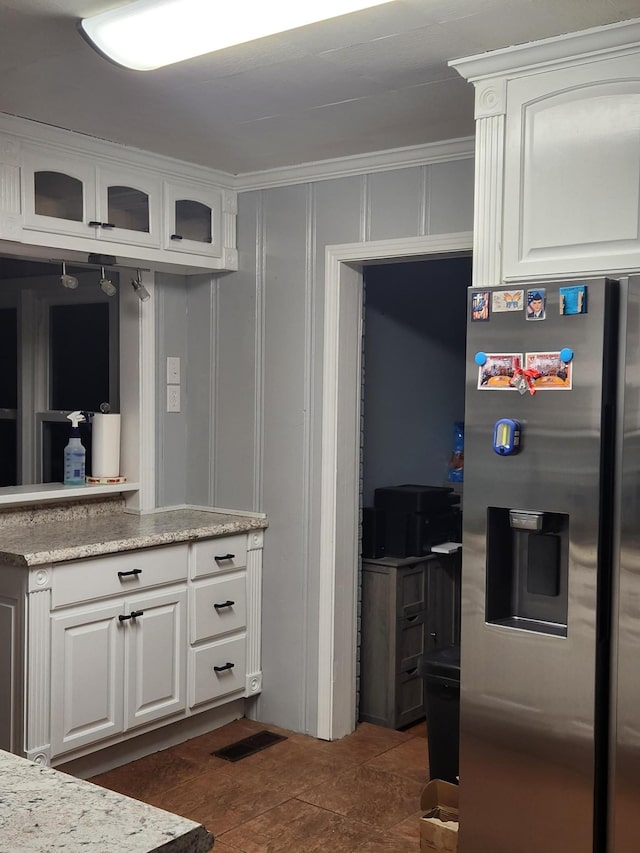 kitchen featuring white cabinets, dark tile patterned floors, stainless steel fridge with ice dispenser, and crown molding