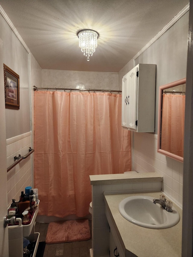 bathroom featuring a textured ceiling, vanity, tile walls, and a chandelier