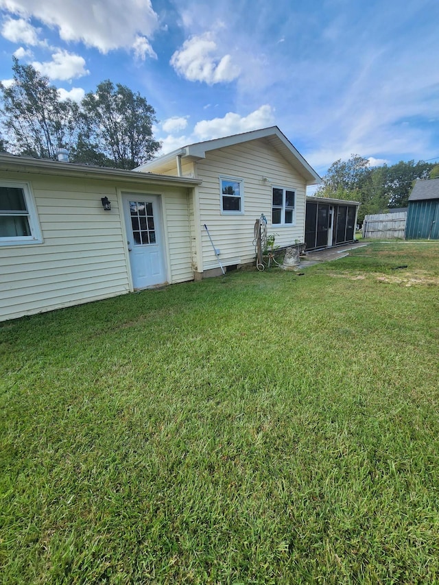 rear view of house with a sunroom and a yard