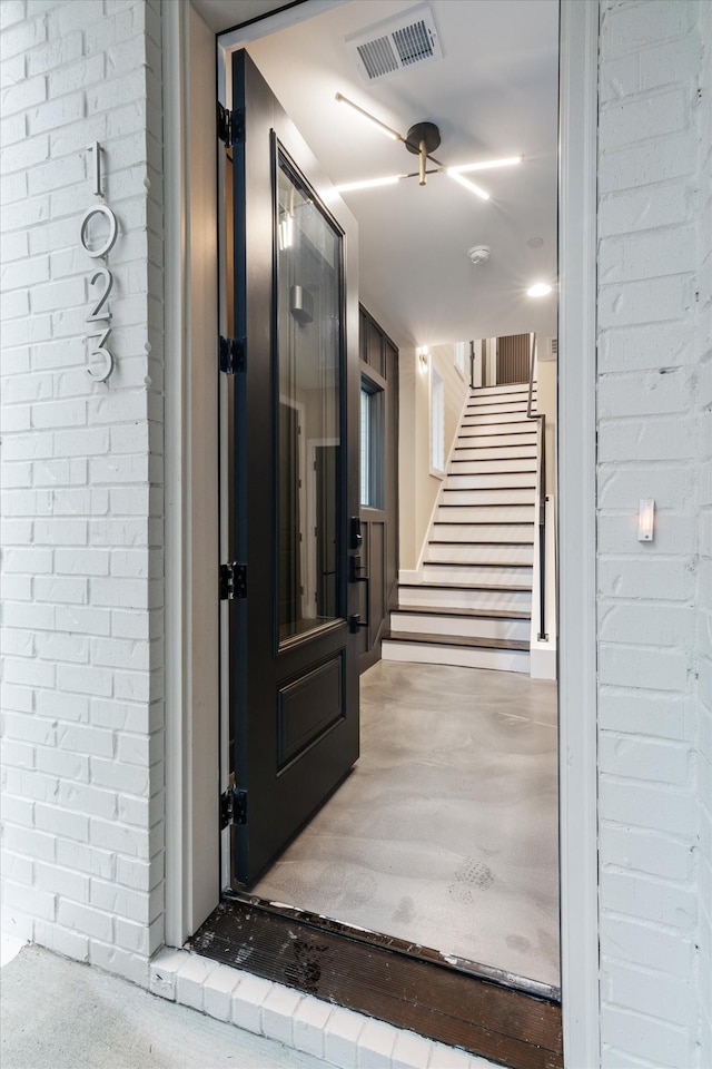 hall with concrete flooring and brick wall