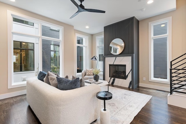 living room with ceiling fan, dark hardwood / wood-style flooring, and a premium fireplace