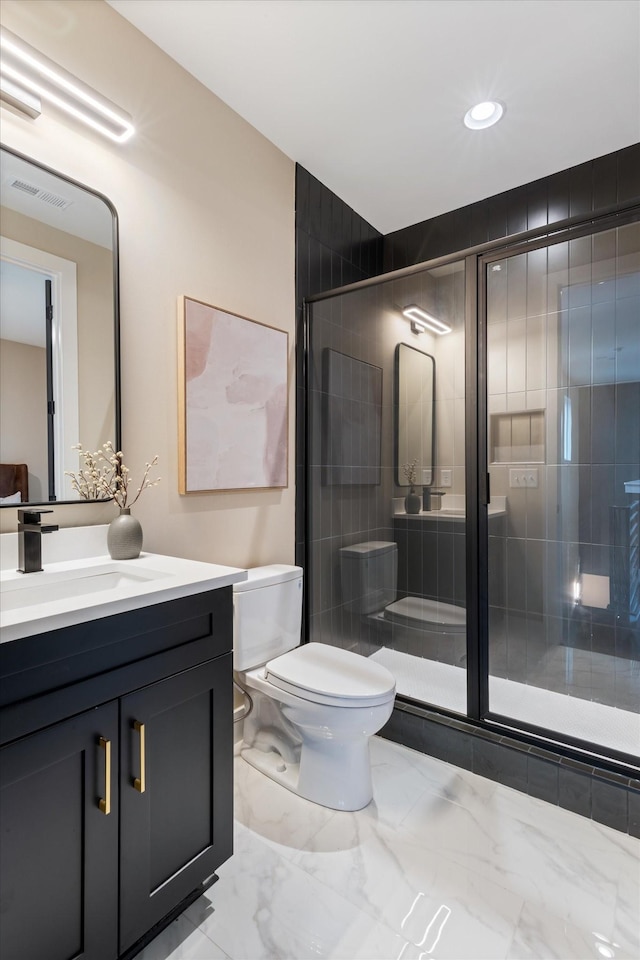 bathroom featuring vanity, toilet, and a shower with shower door