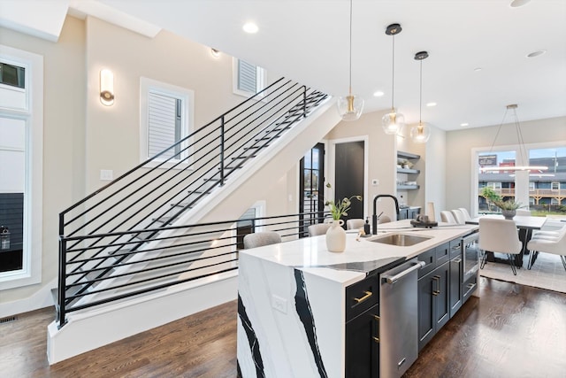 kitchen featuring pendant lighting, sink, an island with sink, appliances with stainless steel finishes, and dark hardwood / wood-style flooring