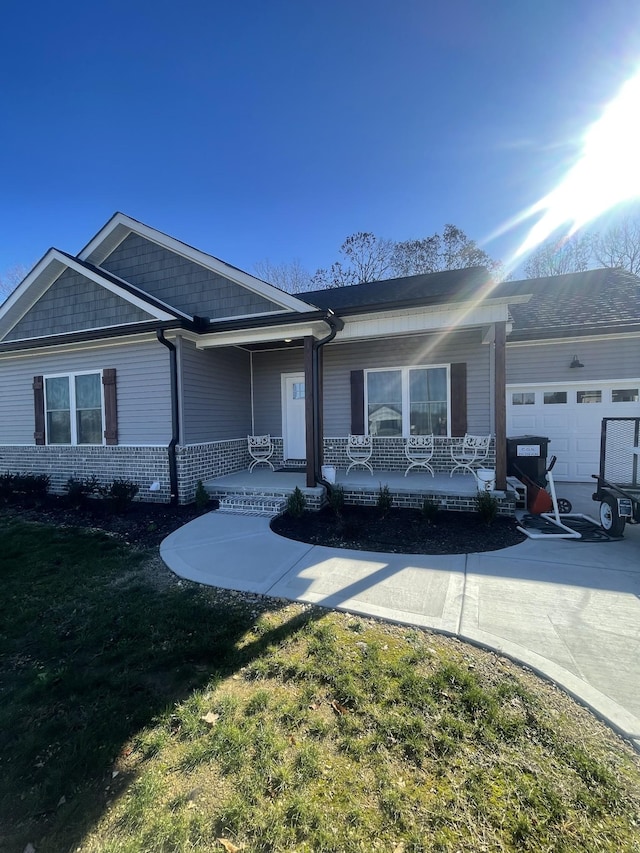 ranch-style home with covered porch, a front yard, and a garage